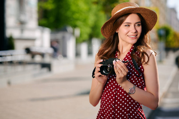 Glückliche junge Frau in lässigem Outfit fotografiert ihre Kamera und läuft im Sommer durch die Stadt - Foto, Bild