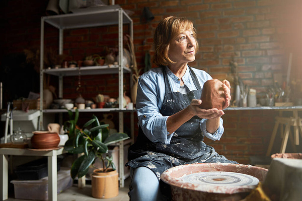 Mooie senior vrouw maken aardewerk in werkplaats - Foto, afbeelding