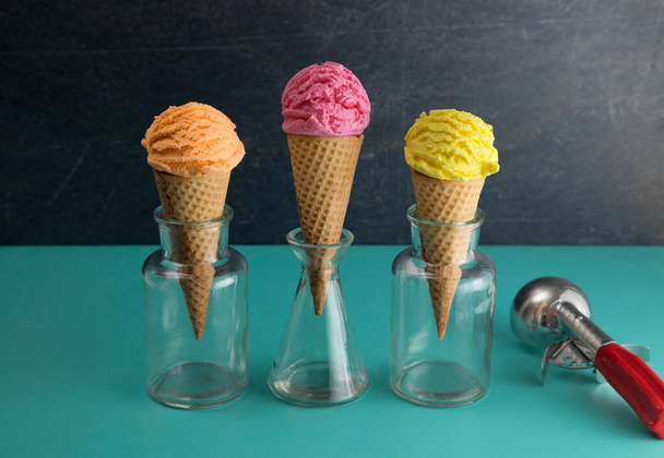 Naranja rosa y amarillo cucharadas de helado en una mesa de Teal - Foto, Imagen