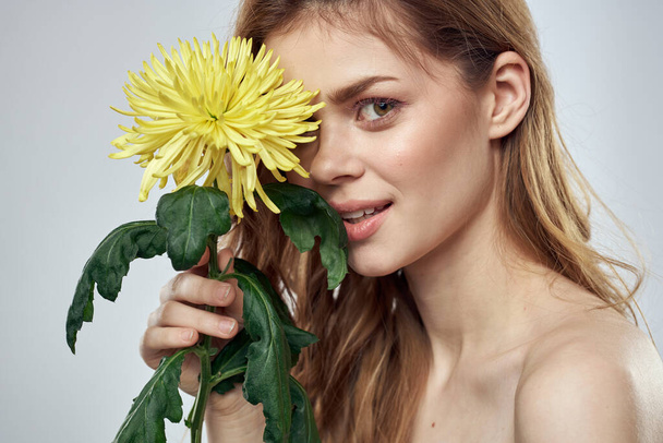 Portret pięknej kobiety z żółtym kwiatem na jasnym tle czarujący uśmiech model rude włosy - Zdjęcie, obraz