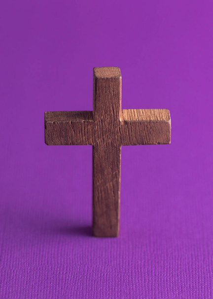 紫色の背景をしたシンプルな木製の十字架 - 写真・画像