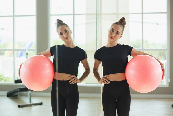 Portrait beautiful woman sportswear holding fit ball or inflatable balls for aerobics and yoga standing mirror side at fitness gym. - Photo, Image