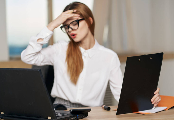 женщина секретарь в белой рубашке рабочий стол ноутбук эмоции работы - Фото, изображение