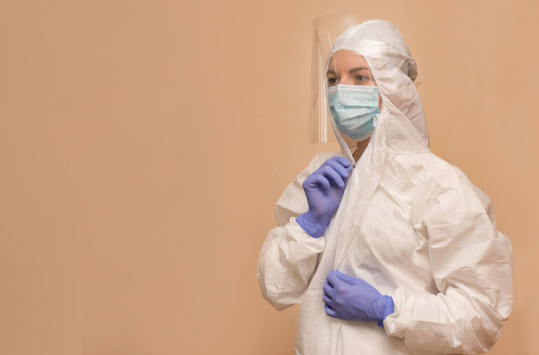 female doctor in a protective suit to combat the coronavirus pandemic covid-2019. Respirator, protective shield, gloves. - Фото, изображение