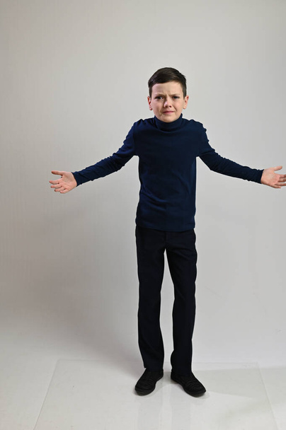 Teen boy in full growth in dark clothes on a white background - Foto, Imagen