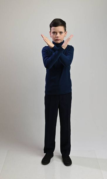 Teen boy in full growth in dark clothes on a white background shows stop - Fotografie, Obrázek