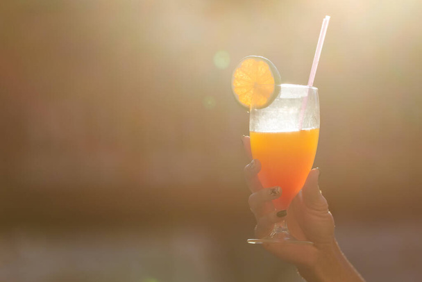 hand holding a cocktail with an orange in glass - Zdjęcie, obraz