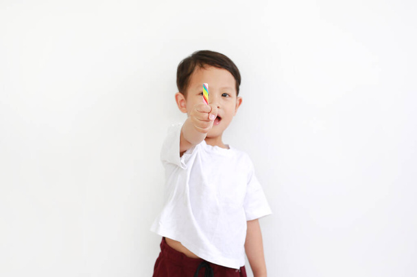 Asian little boy showing lollipop candy on white background. Focus at colorful candy rod in child hand - Foto, immagini