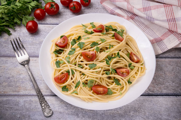 Pasta Spaghetti mit Kirschtomaten und Petersilie auf hellem Hintergrund, köstlich, natürlich. - Foto, Bild