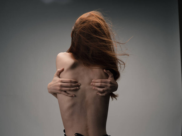 Donna nuda si tocca dietro la schiena con le mani stress emozioni capelli rossi - Foto, immagini