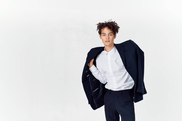  tiener in klassieke pak met jas in de hand en lichte achtergrond bijgesneden weergave van broek  - Foto, afbeelding
