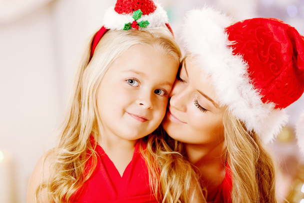 Mother and daughter dressed as Santa celebrate Christmas. Family - Φωτογραφία, εικόνα