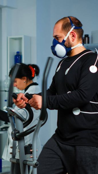 Sportsman running on cross trainer in lab facility for sports performance - Foto, Imagen