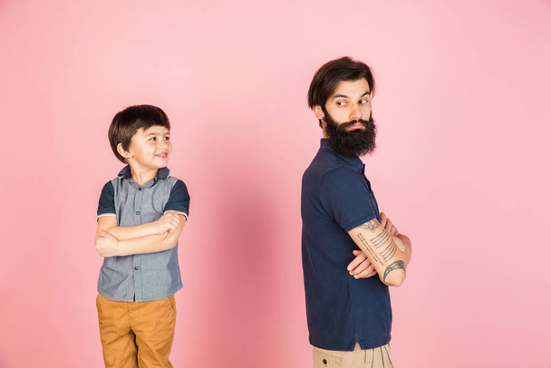 Caucasian man and little boy, father and son isolated over pink background. - Fotografie, Obrázek