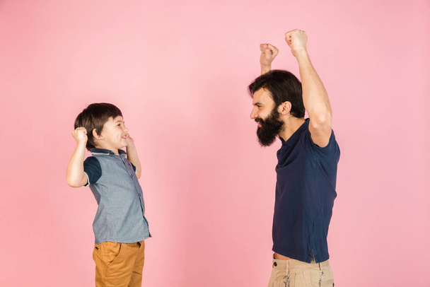 Homem e menino caucasiano, pai e filho isolados sobre fundo rosa. - Foto, Imagem