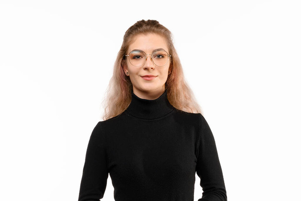 Portrait of smiling happy young woman model, wearing casual clothes, showing positive and confident face expression, standing against white background. Human emotions, facial expression concept - Foto, afbeelding