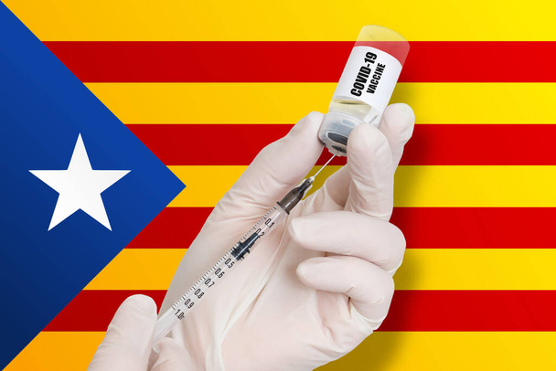 Вакцинация в Каталонии Вакцина для защиты от Ковид-19 на фоне национального флага. - Фото, изображение