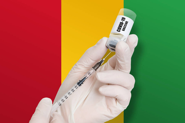 Gine 'de aşı. Ulusal bayrağın arka planında Covid-19 'a karşı koruma aşısı. - Fotoğraf, Görsel