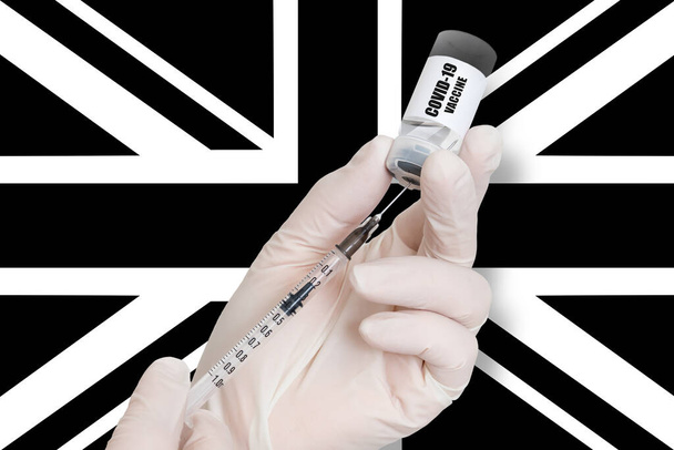 Vaccinatie in Verenigd Koninkrijk. Vaccin ter bescherming tegen Covid-19 op zwart-wit achtergrond van nationale vlag. - Foto, afbeelding
