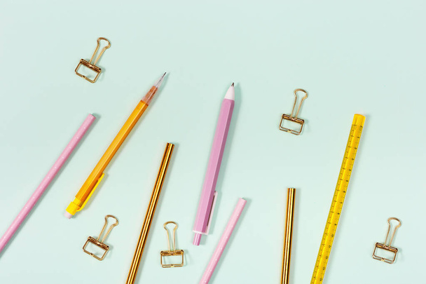 Flat lay with stationery for school or office. Pink and golden colored pencils, pens and metal paperclips. - Fotoğraf, Görsel