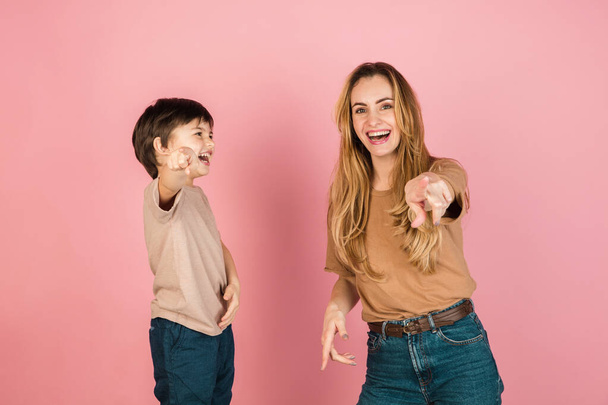 Young woman and little boy, mother and son isolated over pink background. - Photo, Image