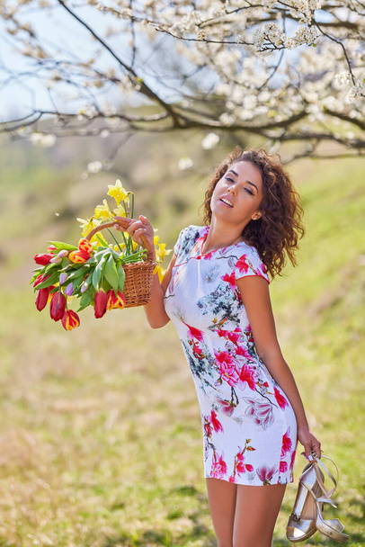 Elinde bir buket çiçekle güzel bir kadın bahar boyunca doğada poz verir. - Fotoğraf, Görsel