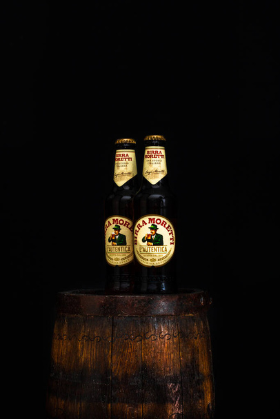 Bottiglia di Birra Moretti birra su botte di legno con sfondo scuro. Foto editoriale illustrativa Bucarest, Romania, 2021 - Foto, immagini