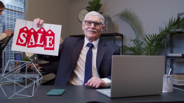 Старший менеджер з бізнесу, який показує Black Friday Sale рекламні написи на офісі - Кадри, відео