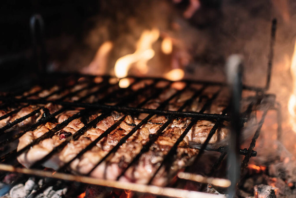 Cooking meat on the grill in a fireplace with embers. - Photo, Image