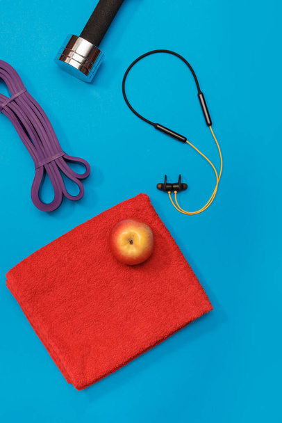 マッサージローラーダンベルスポーツは青の背景にリンゴとタオルをひも - 写真・画像