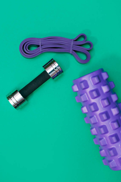 massage roller dumbbell sports leash apple and towel on green background - Photo, Image