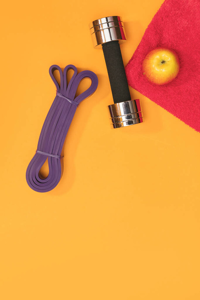 massage roller dumbbell  sports harness apple and towel on yellow background - 写真・画像