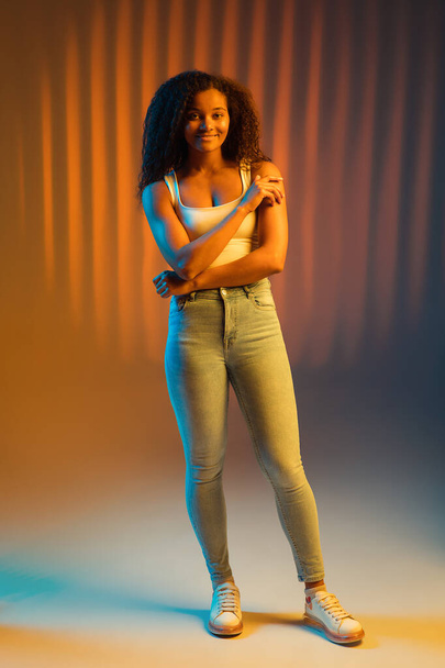 Piękny szczęśliwy African-American dziewczyna izolowane na kolorowe tło w neonie. - Zdjęcie, obraz