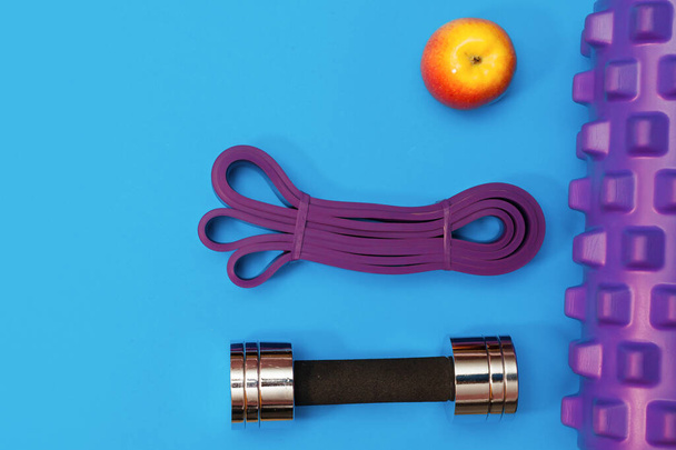 massage roller dumbbell sports leash apple and towel on blue background - Fotografie, Obrázek