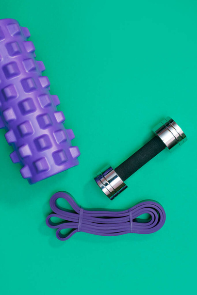 massage roller dumbbell sports leash apple and towel on green background - 写真・画像