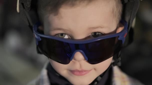 Netter Junge mit Brille posiert für Kamera auf verschwommenem Hintergrund - Filmmaterial, Video