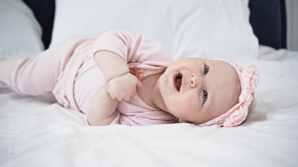 cheerful infant baby girl lying on bed at home - Photo, image