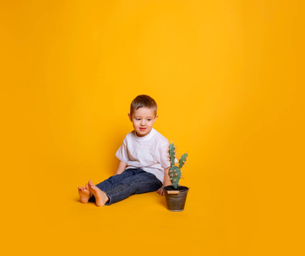 niño pequeño en jeans y una camiseta blanca sobre un fondo amarillo - Foto, imagen