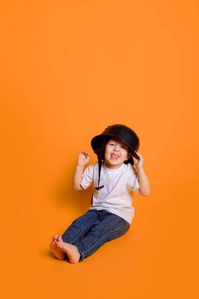 little child in jeans and a white t-shirt on a yellow background - 写真・画像