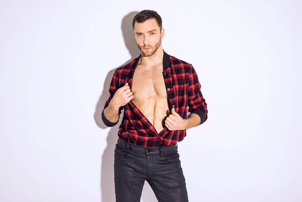 Muscle strong beautiful stripped male model in  blue denim jeans and red shirt on white isolated font background with shadow - Φωτογραφία, εικόνα