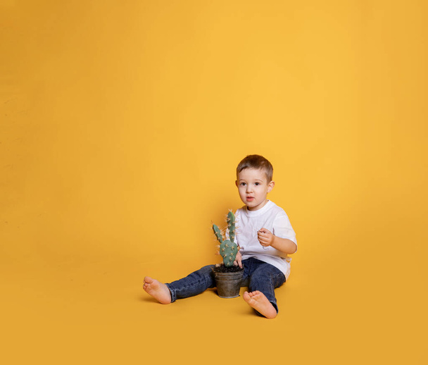 little child in jeans and a white t-shirt on a yellow background - Foto, afbeelding