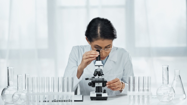 científico afroamericano en gafas mirando a través del microscopio en el laboratorio  - Foto, Imagen