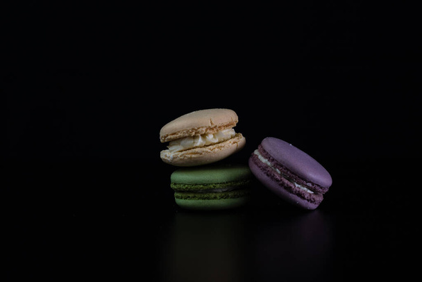 Bunte leckere Macarons isoliert auf schwarzem Hintergrund, Französisch Macarons Dessert - Foto, Bild