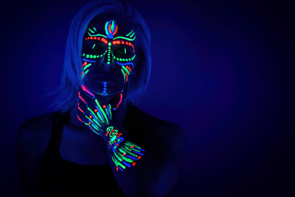 Portrait of woman with neon makeup, which made of fluorescent paint in ultraviolet light. - Foto, immagini