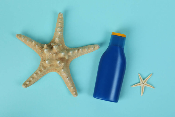 Bottiglia blu di crema solare e stelle marine su sfondo blu - Foto, immagini