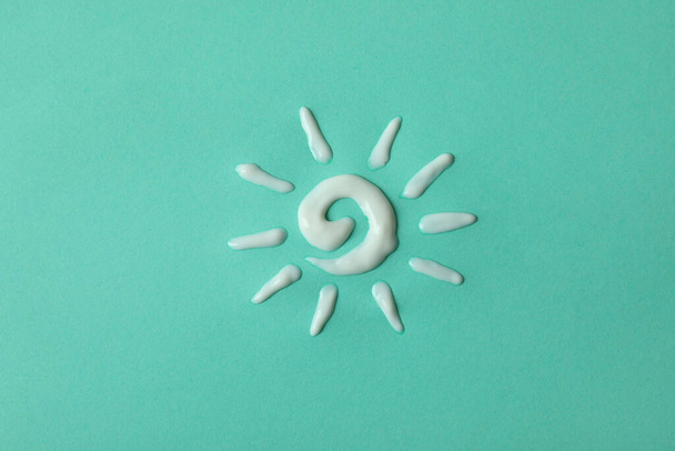Sun made of sunscreen on mint background - Photo, Image