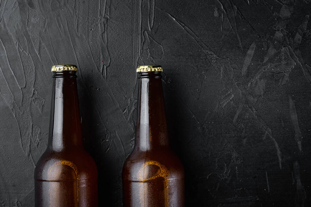 Стеклянные бутылки пива на фоне черного камня, плоский вид сверху, с копировальным местом для текста - Фото, изображение