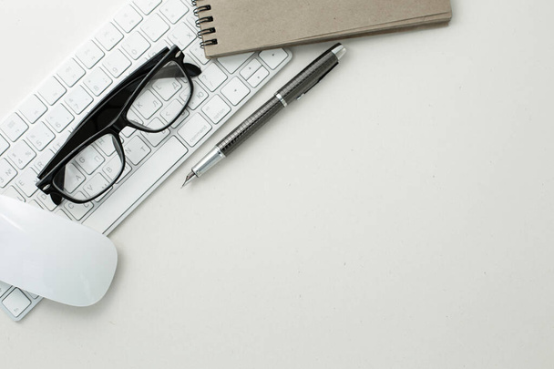 Очки ручка мыши клавиатура и блокнот на белом фоне - Фото, изображение