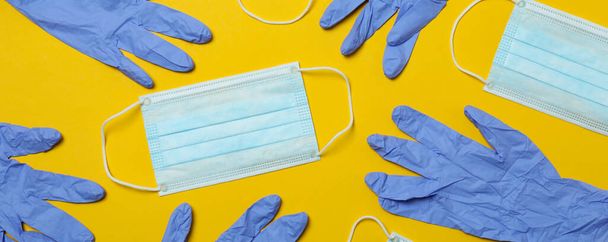 Medizinische Handschuhe und Masken auf gelbem Hintergrund, Ansicht von oben - Foto, Bild