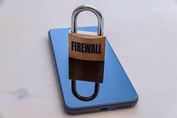 Smartphone com um cadeado que diz "firewall". Segurança de dados, que estão contidos em seus dispositivos eletrônicos.  - Foto, Imagem